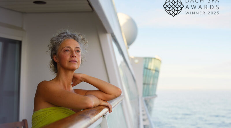 Eine Frau in einem grünen Handtuch lehnt entspannt am Balkon eines Kreuzfahrtschiffs, rechts oben das Logo „DACH Spa Awards Winner 2025“.