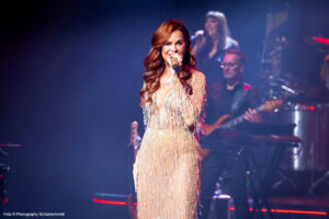 Andrea Berg singt auf der Bühne während eines Konzerts, im Hintergrund spielen Musiker – 2026 wird sie erneut exklusive Konzerte an Bord der Mein Schiff geben.