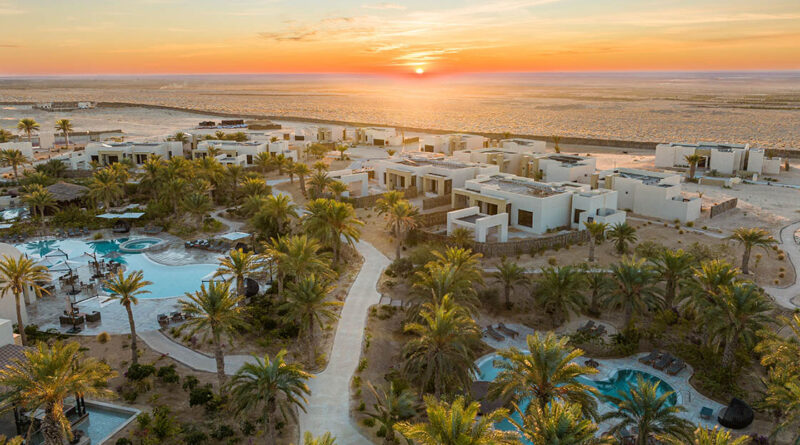 Luxuriöses Wüstenresort mit Palmen, Pools und modernen Villen in Tozeur, Tunesien, bei Sonnenuntergang.