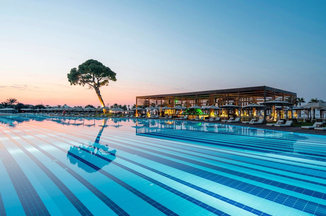 Großer Poolbereich des Rixos Premium Belek bei Sonnenuntergang.