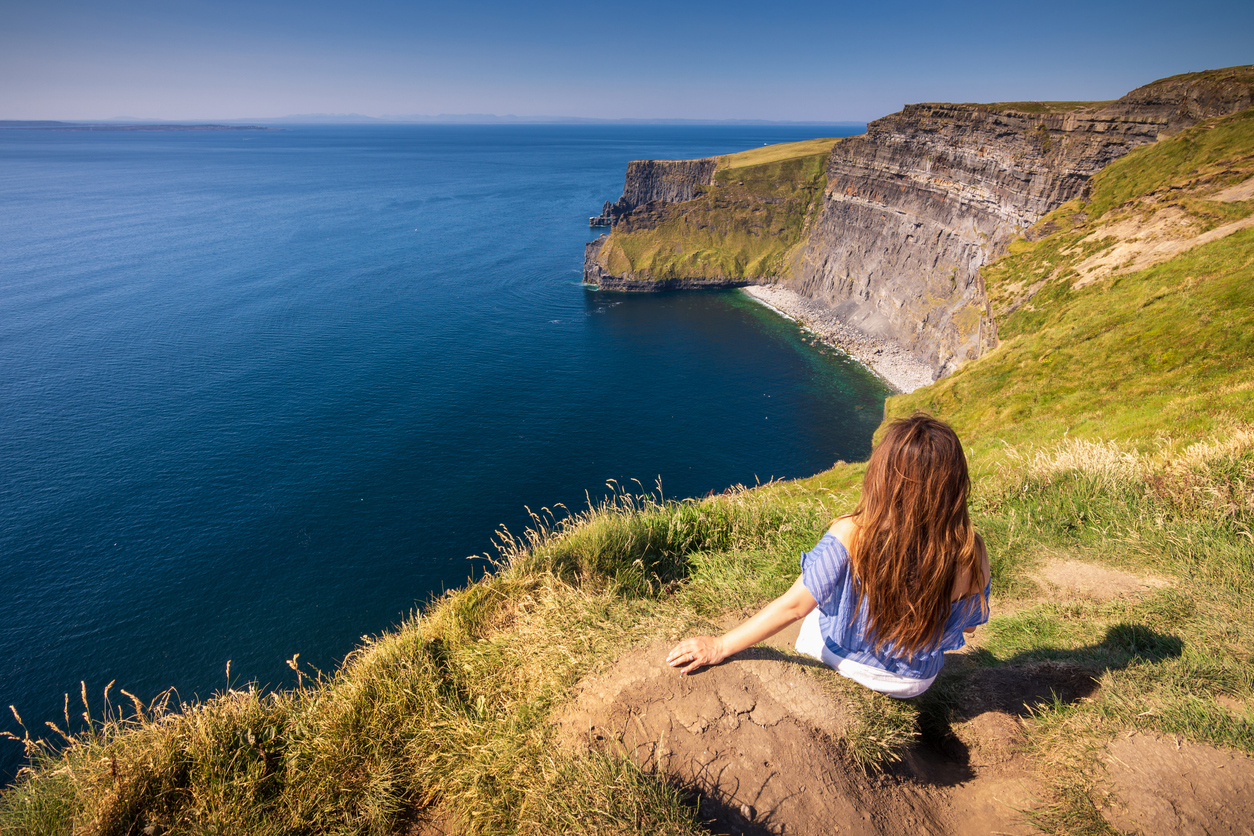 Besucherin an den Cliffs of Moher in Irland – spektakuläre Steilküste und beliebtes Coolcation-Reiseziel an der Atlantikküste
