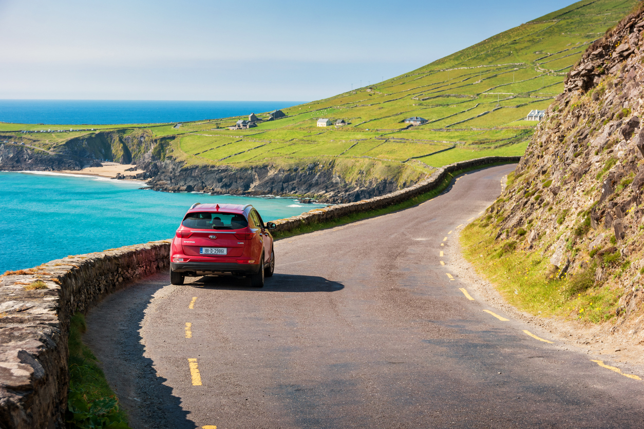 Auto auf der Küstenstraße der Dingle Peninsula in Irland – beliebtes Coolcation-Ziel für Rundreisen und Natururlaub