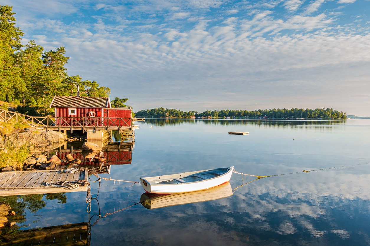 Typisches rotes Schwedenhaus an einem ruhigen See in Schweden – entspannte Coolcation inmitten unberührter Natur und skandinavischer Gelassenheit