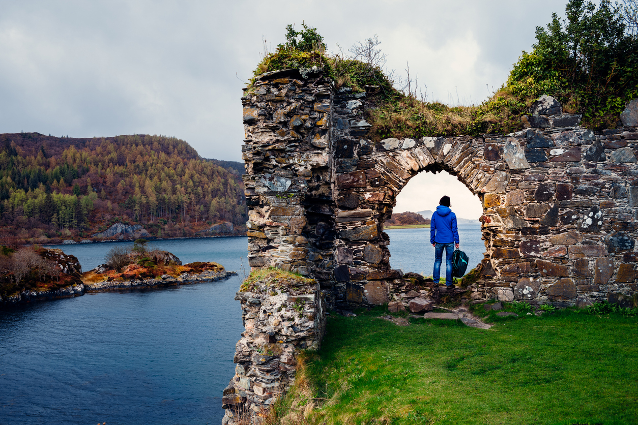 Reisender an einer Burgruine am Loch Carron in den schottischen Highlands – Coolcation zwischen Natur, Geschichte und Küstenlandschaften